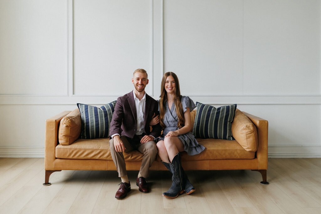 Mikael and Hailee Kohler sitting on a couch while smiling at the camera.