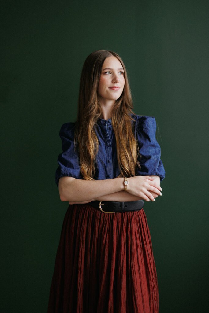 Hailee headshot standing in front of a green wall.
